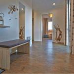 Helle Eingangshalle mit Holzboden und Sitzbank. Dekorative Holzobjekte und Spiegel sind sichtbar.