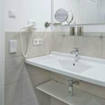 Badezimmer mit Waschbecken, Spiegel und Handtuchhalter.