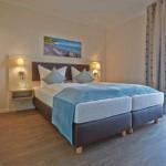 Schlafzimmer mit Doppelbett, Wandbild und Balkontür.