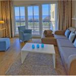 Wohnzimmer mit Sofa, Sessel und Balkonblick aufs Meer.