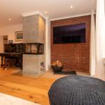 Wohnraum mit Kamin, Klavier und Fernseher an Backsteinwand.