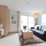 Wohnzimmer mit Sofa, Couchtisch und großen Fenstern.