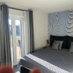 Schlafzimmer mit Bett, Fenster und Wanddekoration.