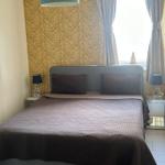 Schlafzimmer mit Bett, Nachttischen und Fenster mit Vorhängen.