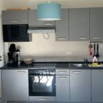 Moderne Küche mit grauen Schränken, Edelstahlspüle und integriertem Ofen.