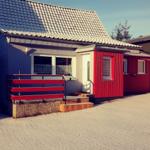 Ein Haus mit rotem Anbau und weißem Dach steht auf schneebedecktem Boden.