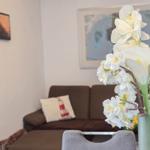 Ein Wohnzimmer mit braunem Sofa, Kissen und Blumenvase.