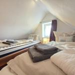 Two beds with bedding and towels under sloped ceilings.