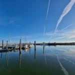 Harbor with boats and clear sky with contrails.