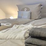 Bed with pillows and towels in a bedroom with sloped ceiling.