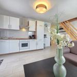 Kitchen with white built-in cabinets and dining area with sofa and flower vase.