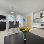 Kitchen with dining area and TV. Vase with tulips on table.