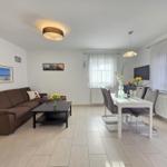 Living and dining area with sofa, table and chairs. Windows with curtains.