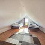 Two beds in an attic room with wooden floor and window.