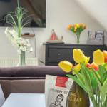 Living room with TV, flowers, and a table with tulips.