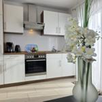 Kitchen with white cabinets, stove, and window with white curtains.