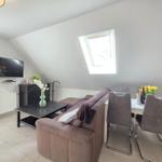 Living and dining area with sofa, TV, and skylight.