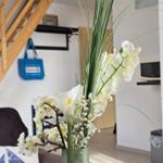 Flower arrangement in foreground, stairs and kitchen area behind.