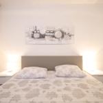 Schlafzimmer mit Bett, Nachttischen und Wandbild.