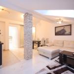 Wohnbereich mit Sofa, Esstisch und Küchenzeile. Steinpfeiler und Dachfenster.