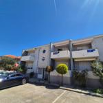 Moderne Wohnanlage mit Balkonen und gepflegtem Außenbereich unter blauem Himmel.