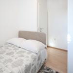 Schlafzimmer mit Bett, Teppich und Holzboden. Tür und Wand sind weiß.