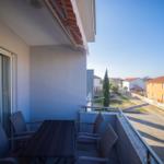 Terrasse mit Tisch und Stühlen, Blick auf Straße und Häuser.