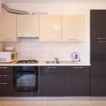 Küche mit dunklen Schränken, Herd, Spüle und Kühlschrank.