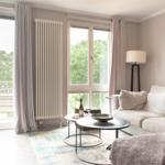 Wohnzimmer mit Sofa, Couchtisch und Blick auf Balkon mit Bäumen.