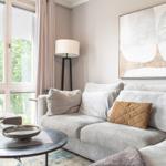 Ein Wohnzimmer mit Sofa, Tisch und Fensterblick auf Bäume.