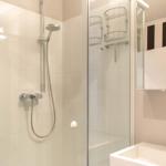 Dusche mit Duschbrause und Handbrause, Spiegel und Waschbecken im Badezimmer.