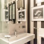 Badezimmer mit Waschbecken, Spiegel und Wandbildern an schwarz-weißen Streifen.