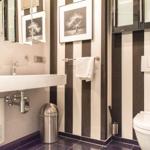 Badezimmer mit schwarz-weißen Streifen, Waschbecken, Toilette und Spiegel.