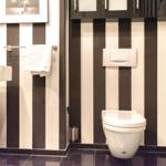 Badezimmer mit schwarz-weißen Streifen, Toilette, Waschbecken und Spiegel.