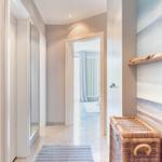 Flur mit Wickerkorb und Wandbild, Tür zu Wohnzimmer sichtbar.