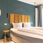 Schlafzimmer mit Bett, Kopfteil, Wandspiegel und Fenster