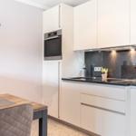 Küche mit weißen Schränken, schwarzer Arbeitsplatte und integriertem Ofen.