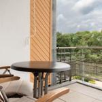 Terrasse mit Tisch und Stuhl, Blick auf grüne Bäume und Himmel.