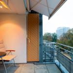 Terrasse mit Sitzgruppe und Blick auf Grünfläche und Gebäude