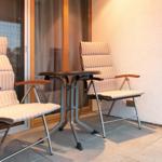 Terrasse mit zwei Sesseln und Tisch. Hintergrund: Glas-Tür und Wand.