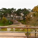 Vom Balkon aus Blick auf einen Teich, einen Weg und ein Gebäude im Wald.
