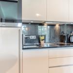 Moderne Küche mit Edelstahlspüle, dunkler Arbeitsplatte und integriertem Kühlschrank.