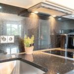 Küche mit schwarzer Arbeitsplatte, Edelstahlspüle und Kaffeemaschine.