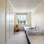 Bedroom with two beds, wardrobe, and window with view outside.