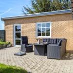 Terrace with seating group, recliner, and table in front of a brick house.