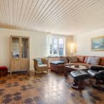 Living room with sofa, chair, and TV. Wooden ceiling and tiled floor.