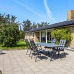 Terrace with table and chairs in front of a house with garden.