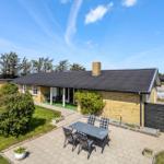 A house with terrace, garden, and table with chairs under blue sky.