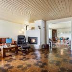 Living room with fireplace, sofa, and TV. Hallway leads to dining room.