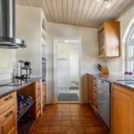 Kitchen with wooden cabinets, stainless steel sink and terracotta floor
